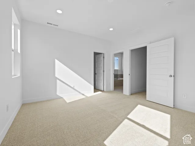 Neutral-toned carpeting, recessed ceiling lighting, and multi-panel interior doors