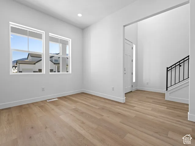 Interior space featuring wood-finish flooring, recessed lighting, dual-pane windows, and a staircase with a black metal railing