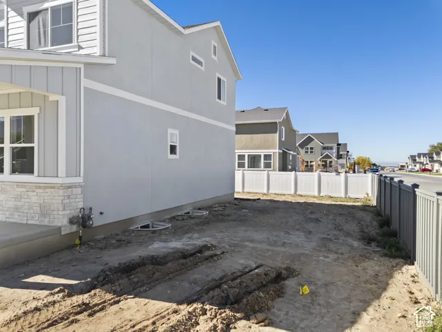 Two-story exterior featuring light-toned stucco, board-and-batten siding, stone veneer accents, and white vinyl perimeter fencing