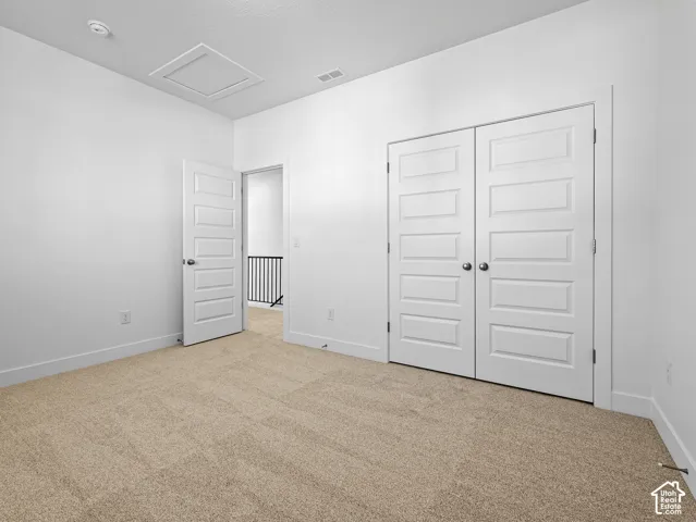 Neutral-toned wall-to-wall carpeting, white five-panel interior doors, and double-door closet entry