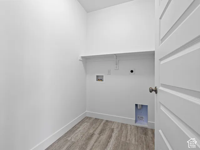 Utility space featuring wood-finish flooring, a built-in shelf, and recessed water and dryer connections