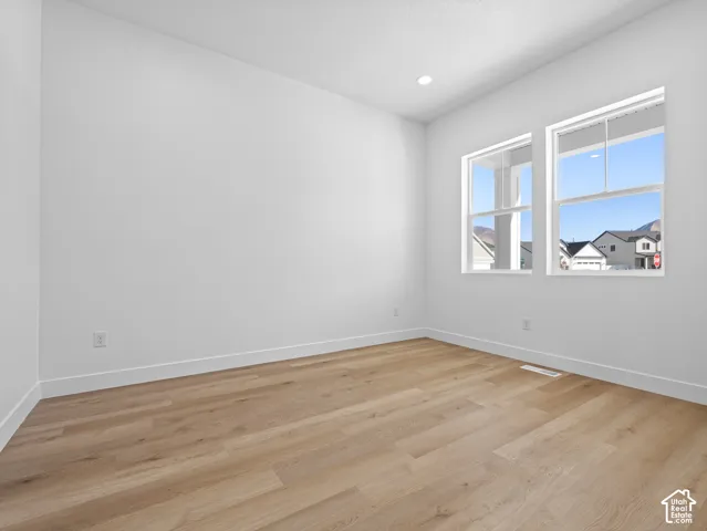 Neutral-toned interior room featuring wood-finish flooring, dual windows, and recessed ceiling lighting
