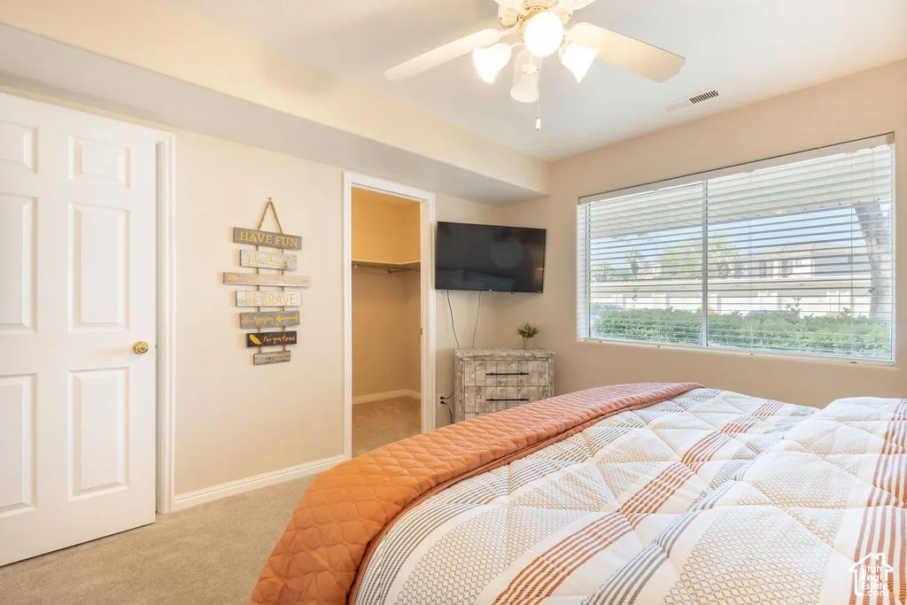 Recessed lighting, ceiling fan with light, large window with blinds, carpeted flooring, and a walk-in closet