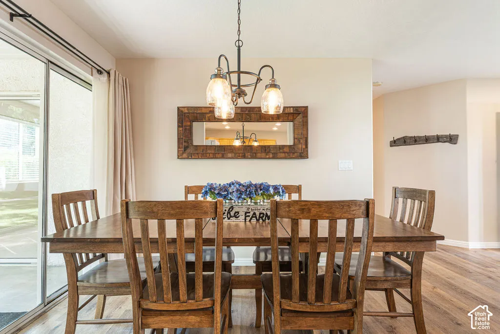 Dining area featuring wood-finish flooring, a wall-mounted mirror, and an overhead chandelier with glass shades