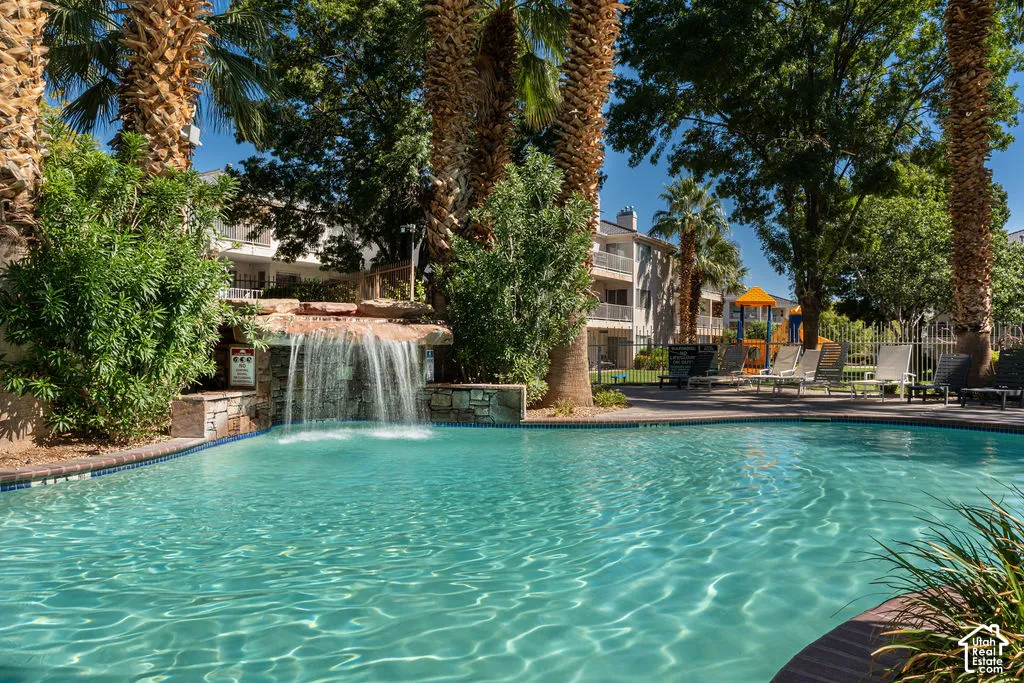Pool with waterfall feature, surrounded by mature palm trees and lush landscaping