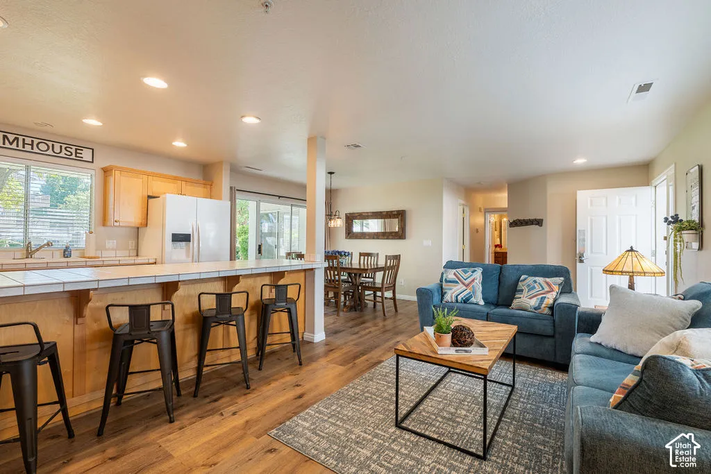 Open-concept living space with wood-finish flooring, recessed lighting, and a kitchen featuring light wood cabinetry
