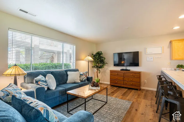 Wood-finish flooring throughout, complemented by a large window with horizontal blinds