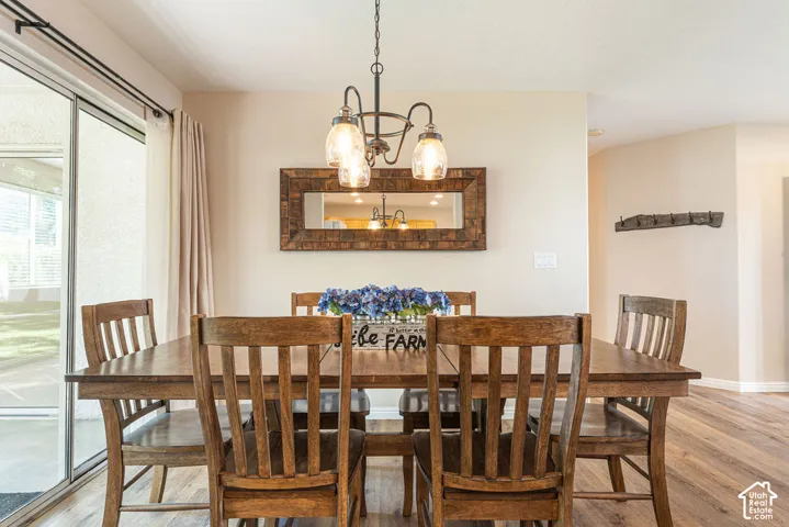 Dining area featuring wood-finish flooring, a wall-mounted mirror, and an overhead chandelier with glass shades