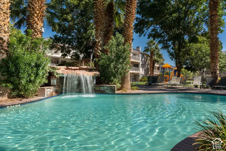Pool with waterfall feature, surrounded by mature palm trees and lush landscaping