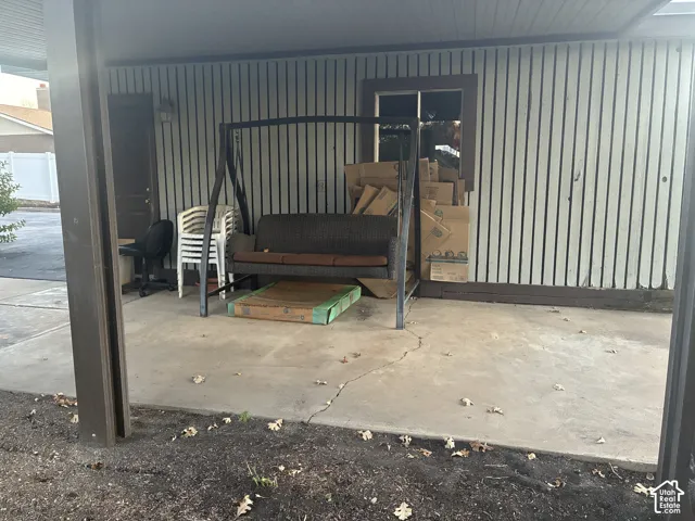 Covered exterior concrete patio featuring vertical siding and a window