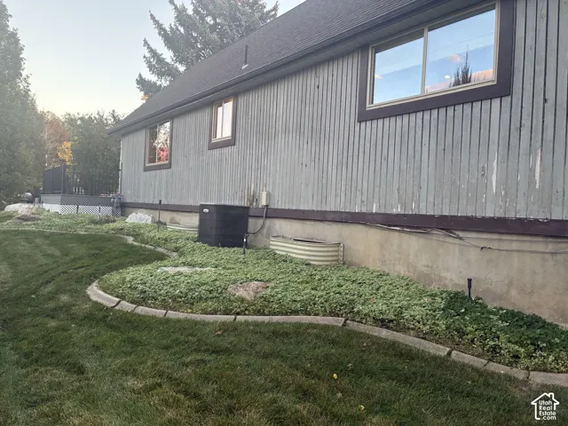 Vertical wood-panel siding exterior, concrete foundation, landscaped ground cover with stone edging, and sliding windows