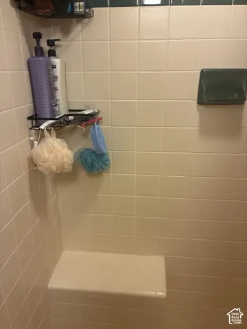 Shower enclosure featuring square wall tile, a built-in tile bench, and a recessed soap niche