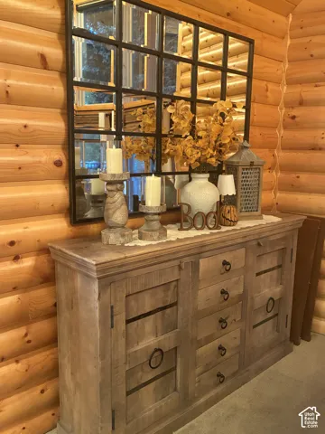 Natural rounded log wall construction featuring a grid-patterned wall mirror with a dark metal frame