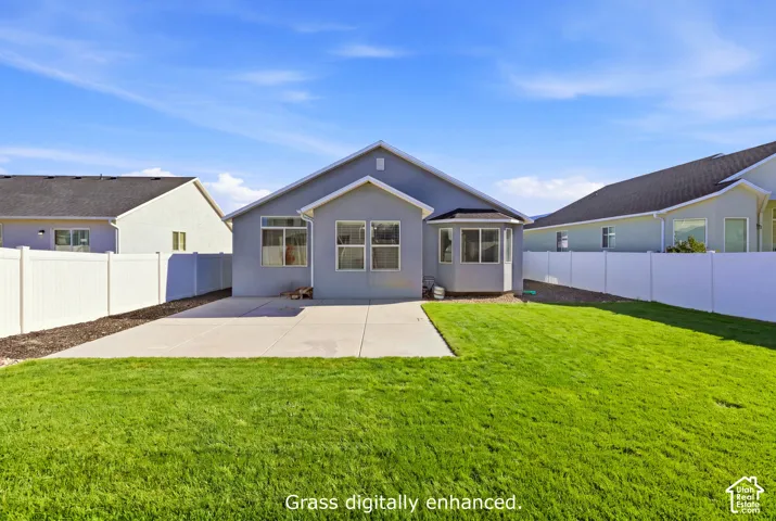 Backyard featuring a concrete patio, a grass lawn, and perimeter vinyl fencing