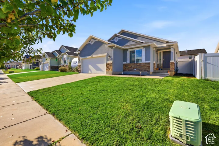 Single-story residence featuring a stone and stucco facade, an attached two-car garage, white vinyl privacy fencing, and a concrete driveway