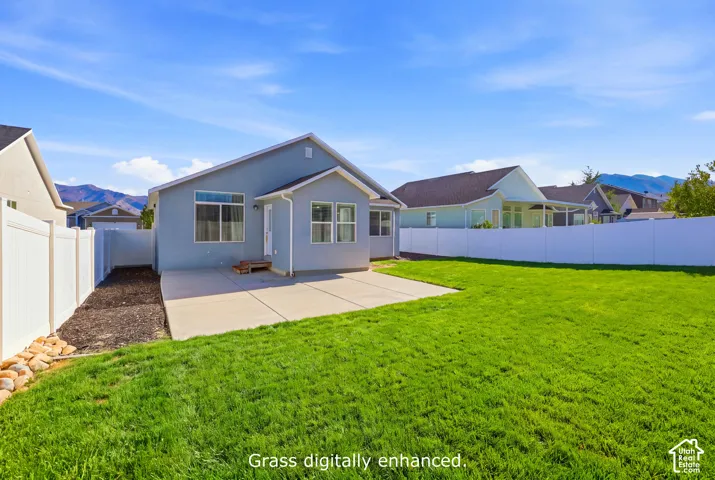 Rear exterior featuring a concrete patio, white vinyl fencing, and mountain backdrop