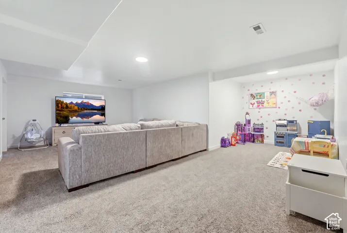 Open-concept interior space featuring wall-to-wall carpeting, neutral wall finishes, recessed lighting, and a window