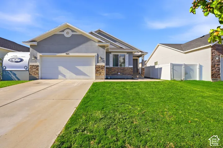 Single-story residence featuring a multi-textured exterior of stone veneer and stucco, a gabled roofline, an attached two-car garage, and white vinyl privacy fencing