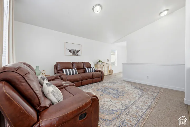 Vaulted ceiling with dual flush-mount light fixtures, neutral wall finish, and wall-to-wall carpeting