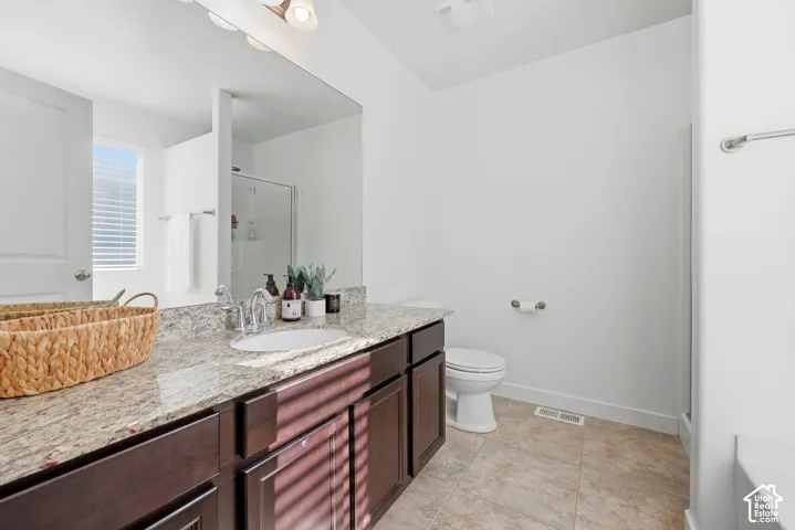 Bathroom featuring dark-finish wood cabinetry, stone-style countertop with an integrated basin, large wall-mounted mirror, and tile flooring