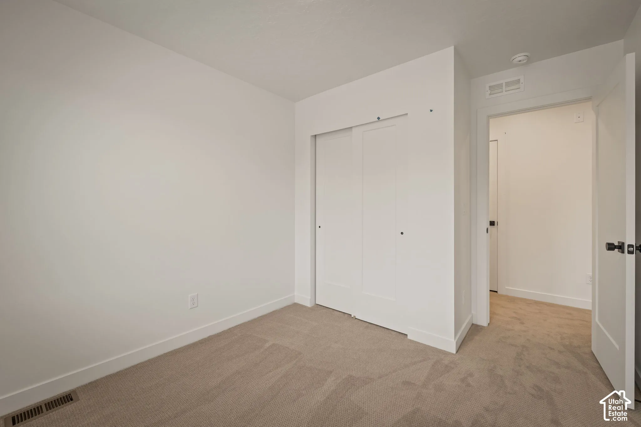 Neutral-toned carpeting, white sliding closet doors, and solid-core interior doors with matte black hardware