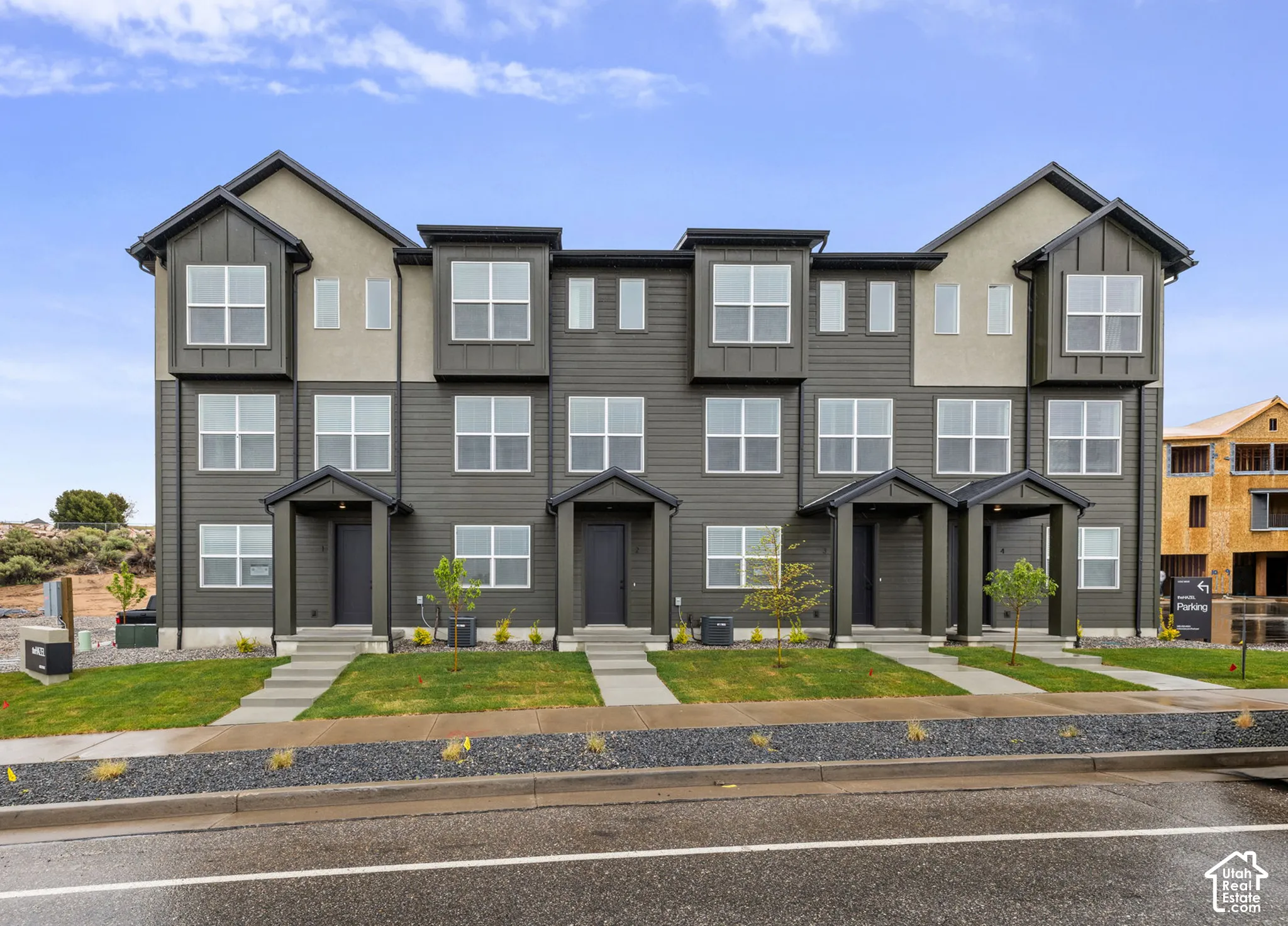 Multi-level townhouse exterior featuring horizontal siding, stucco accents, multiple bay windows, and covered front entryways
