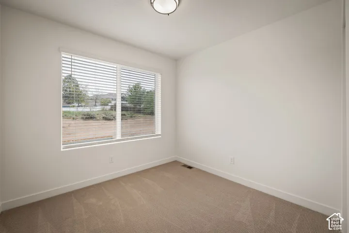 Neutral-toned carpeted flooring, window with installed horizontal blinds, and ceiling-mounted flush light fixture