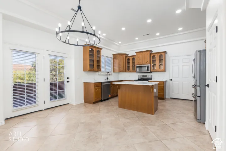 Kitchen featuring wood cabinetry, central island, stone-finish countertops, tile flooring, and a decorative metal chandelier