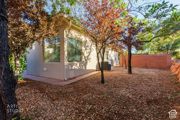 Stucco exterior with large picture windows, concrete pathway, decorative rock ground cover, and masonry perimeter wall
