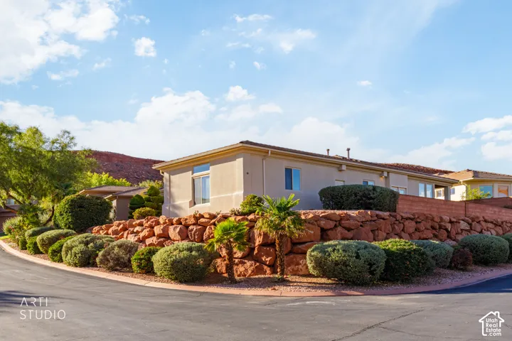 Single-story exterior featuring a natural stone retaining wall, desert landscaping, and mountain backdrop