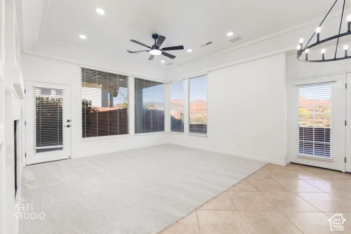 Living area featuring a tray ceiling, recessed lighting, tile and carpeted flooring, large windows with mountain scenery, and a wrought-iron style chandelier