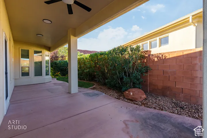 Covered concrete patio featuring recessed lighting, a ceiling fan, and a red masonry privacy wall