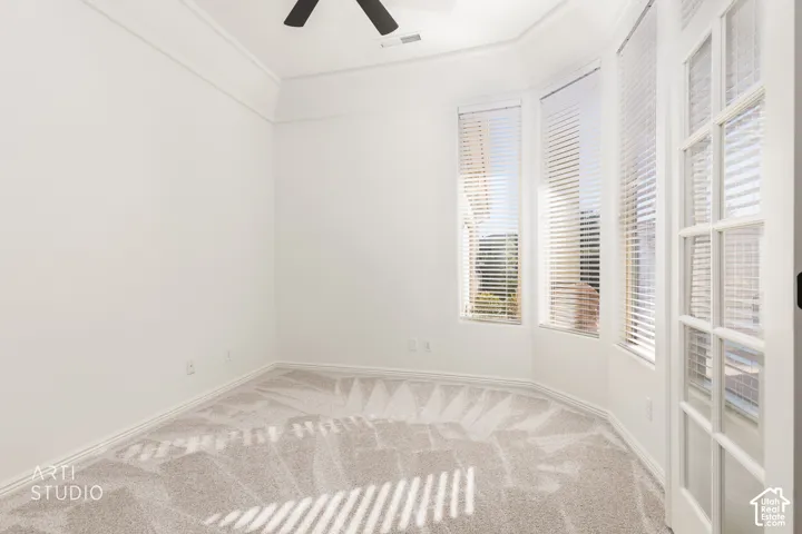 Tray ceiling, bay window, wall-to-wall carpeting, ceiling fan, and French-style door