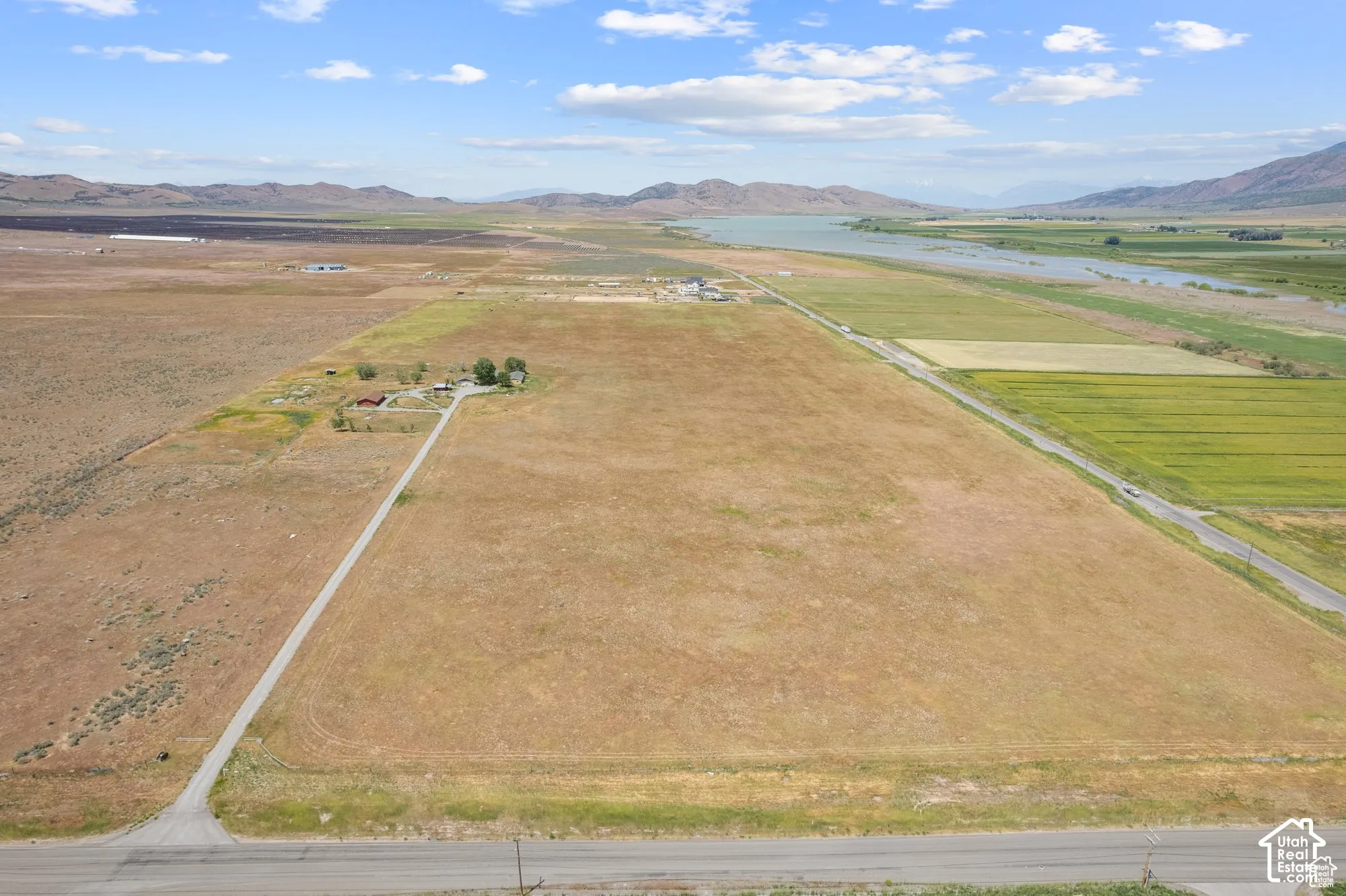Expansive acreage featuring a private gravel driveway, multiple outbuildings, and a prominent mountain and river backdrop