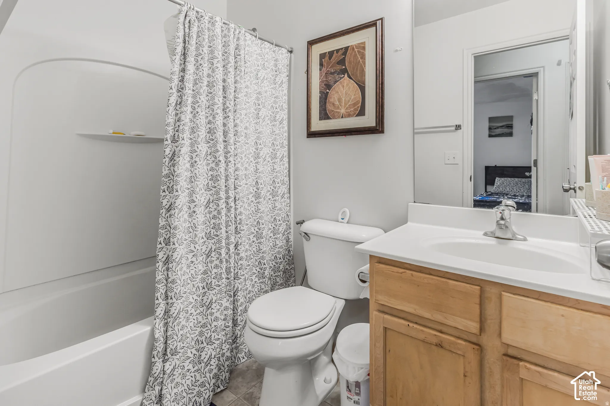 Bathroom featuring a wood-finish vanity with a white countertop, integrated sink, large wall mirror, and a tub-shower combination with a molded surround
