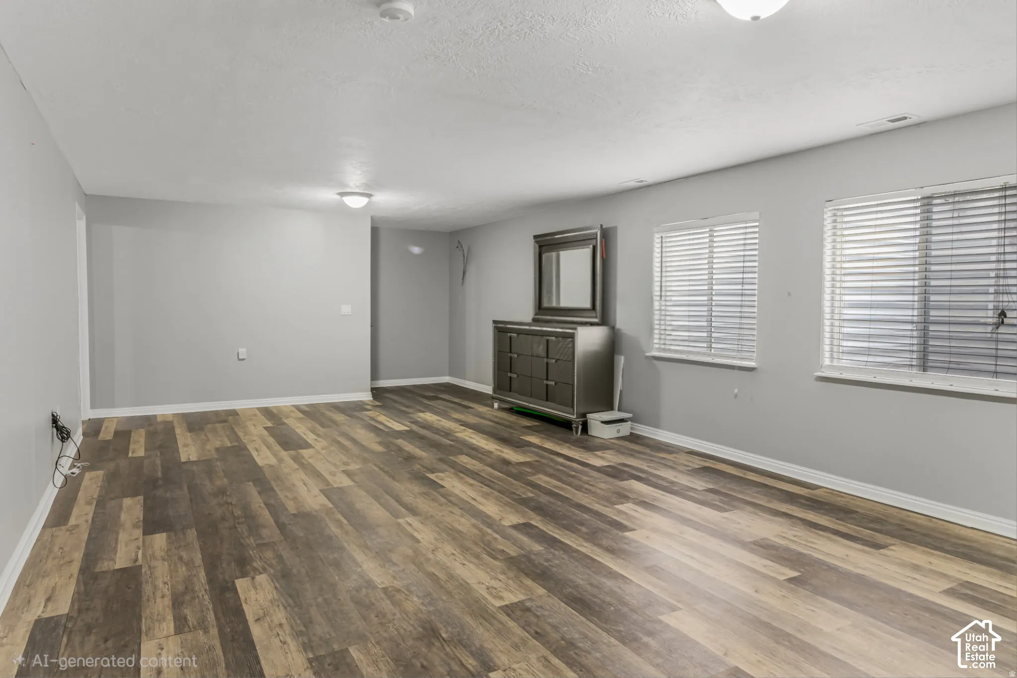 Spacious interior featuring wood-finish flooring, neutral wall paint, and two windows with horizontal blinds