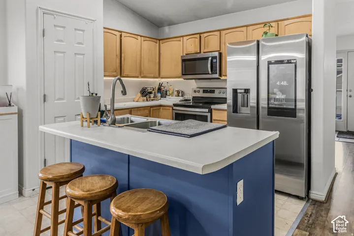 Kitchen featuring wood cabinetry, stainless steel appliances, under-cabinet lighting, and a central island with a solid surface countertop