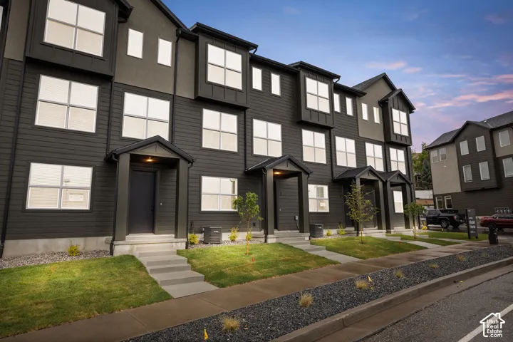 Multi-story townhouse exterior featuring dark horizontal siding, pitched rooflines, grid-patterned windows, and covered front entryways