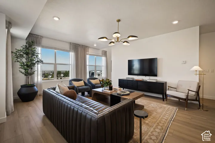 Living area featuring wood-finish flooring, recessed lighting, expansive windows, and a modern multi-arm chandelier