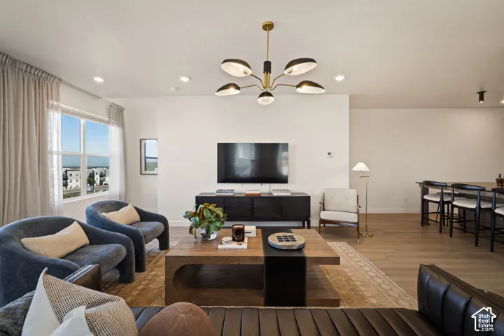 Open-concept living space featuring wood-finish flooring, recessed lighting, and a contemporary multi-arm chandelier