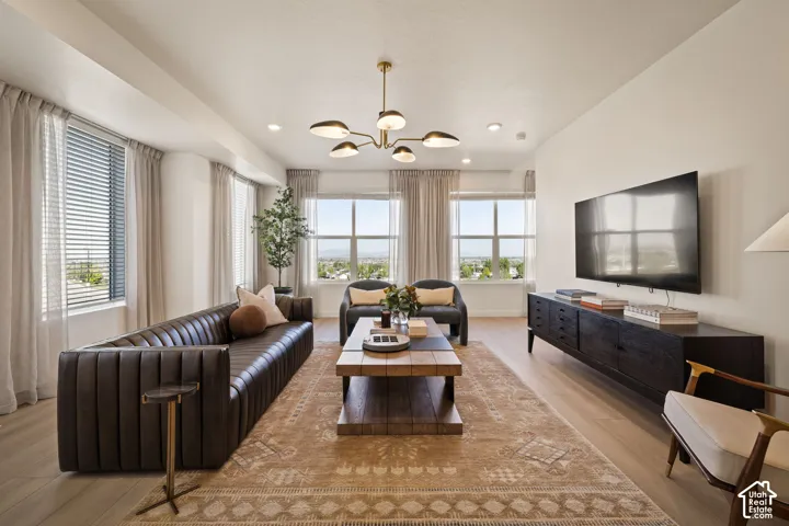 Living area featuring light-toned wood-finish flooring, multi-pane windows with natural light, and a modern six-arm chandelier