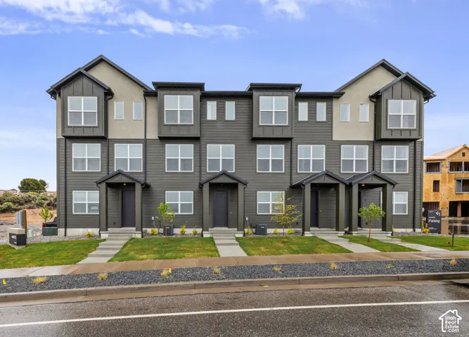 Multi-level townhouse exterior featuring horizontal siding, stucco accents, multiple bay windows, and covered front entryways