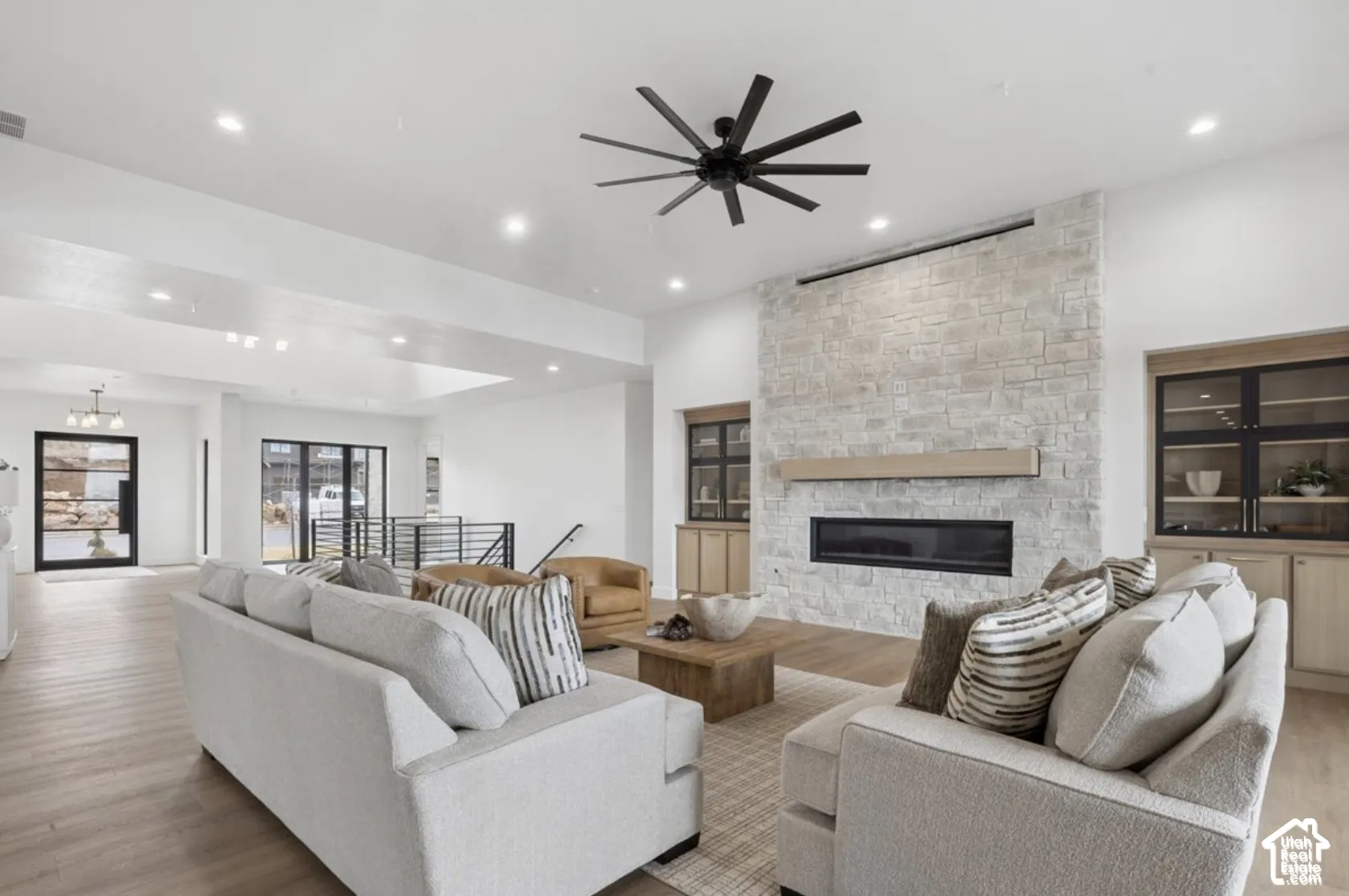 Living space featuring a stone-clad linear fireplace, floating wood mantel, custom built-in cabinetry, recessed lighting, and a multi-blade ceiling fan