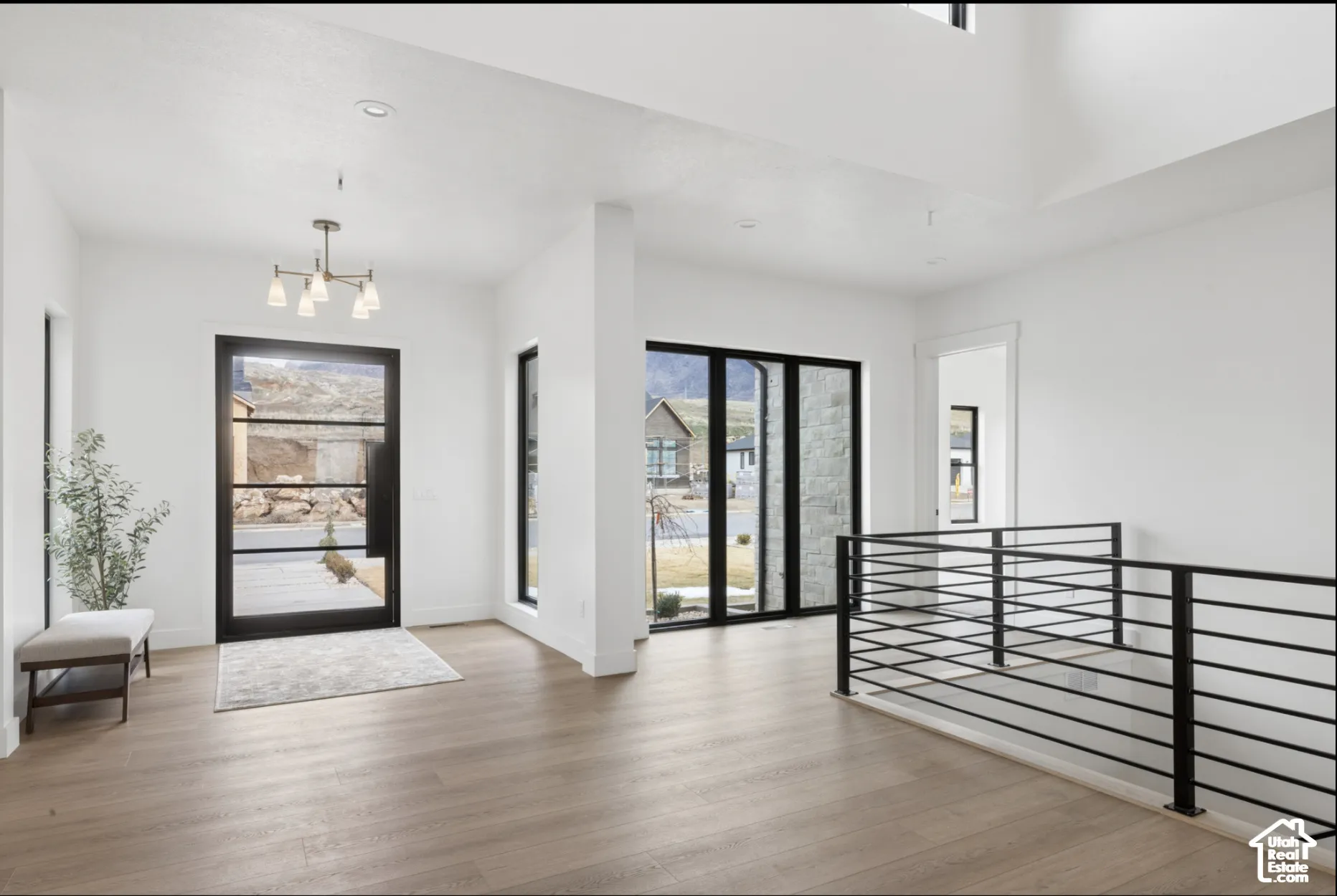 Entryway featuring wood-finish flooring, a multi-pane black-framed glass door, recessed lighting, a modern chandelier, and a metal horizontal-bar railing