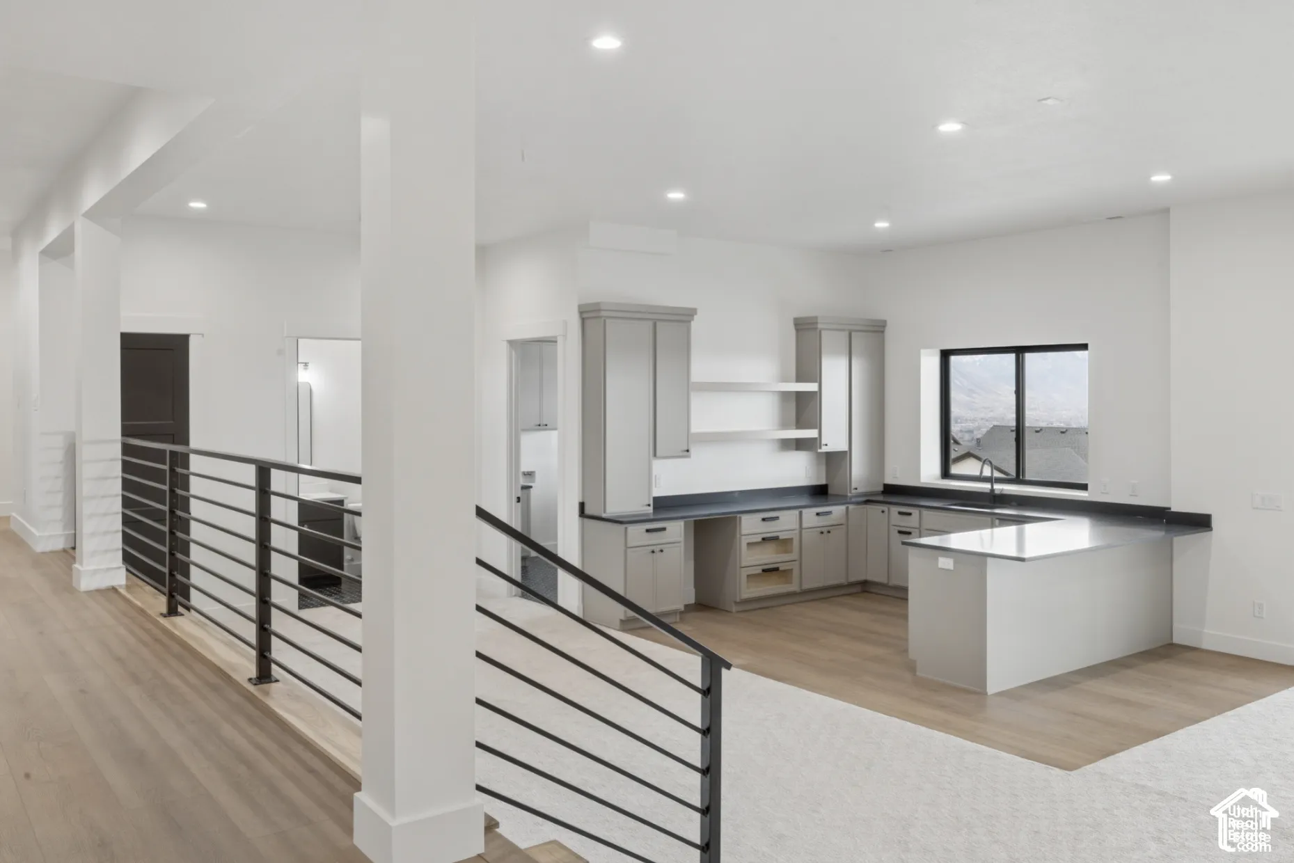 Kitchen featuring grey shaker-style cabinetry, dark stone-finish countertops, wood-finish flooring, recessed lighting, and a metal horizontal-bar railing