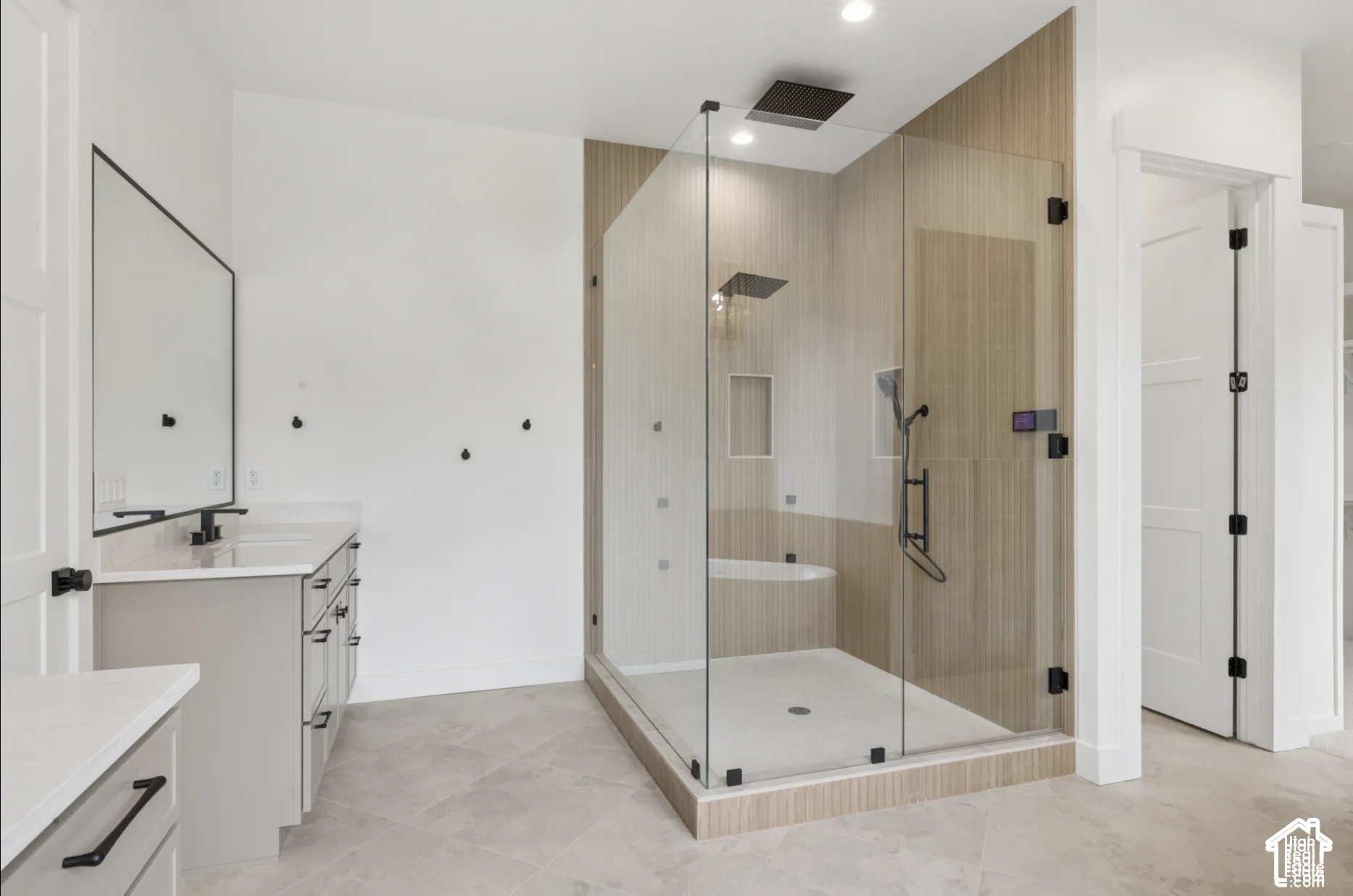 Walk-in shower with frameless glass enclosure, ceiling-mounted rainfall showerhead, and wall-tile surround