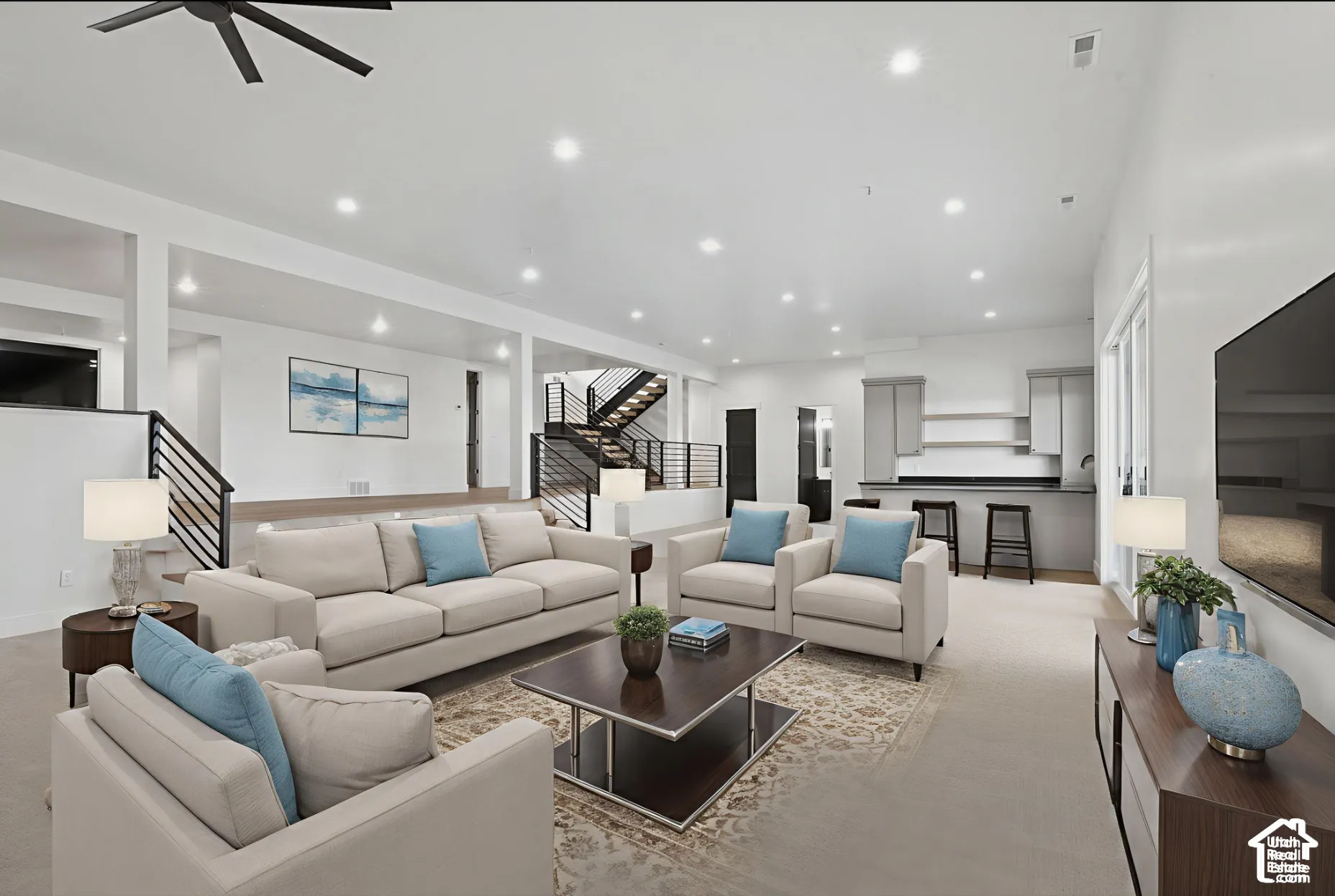 Open-concept interior featuring recessed lighting, a wet bar with shaker-style cabinetry, a multi-level staircase with metal railings, and neutral wall-to-wall carpeting