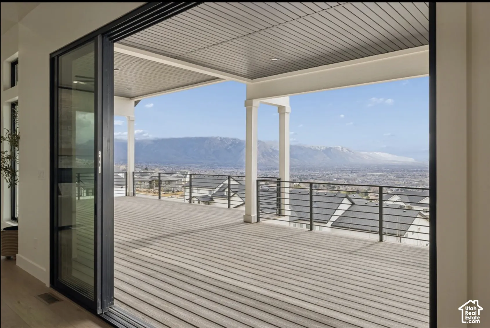 Covered deck featuring composite decking, horizontal cable railing, recessed lighting, and mountain scenery