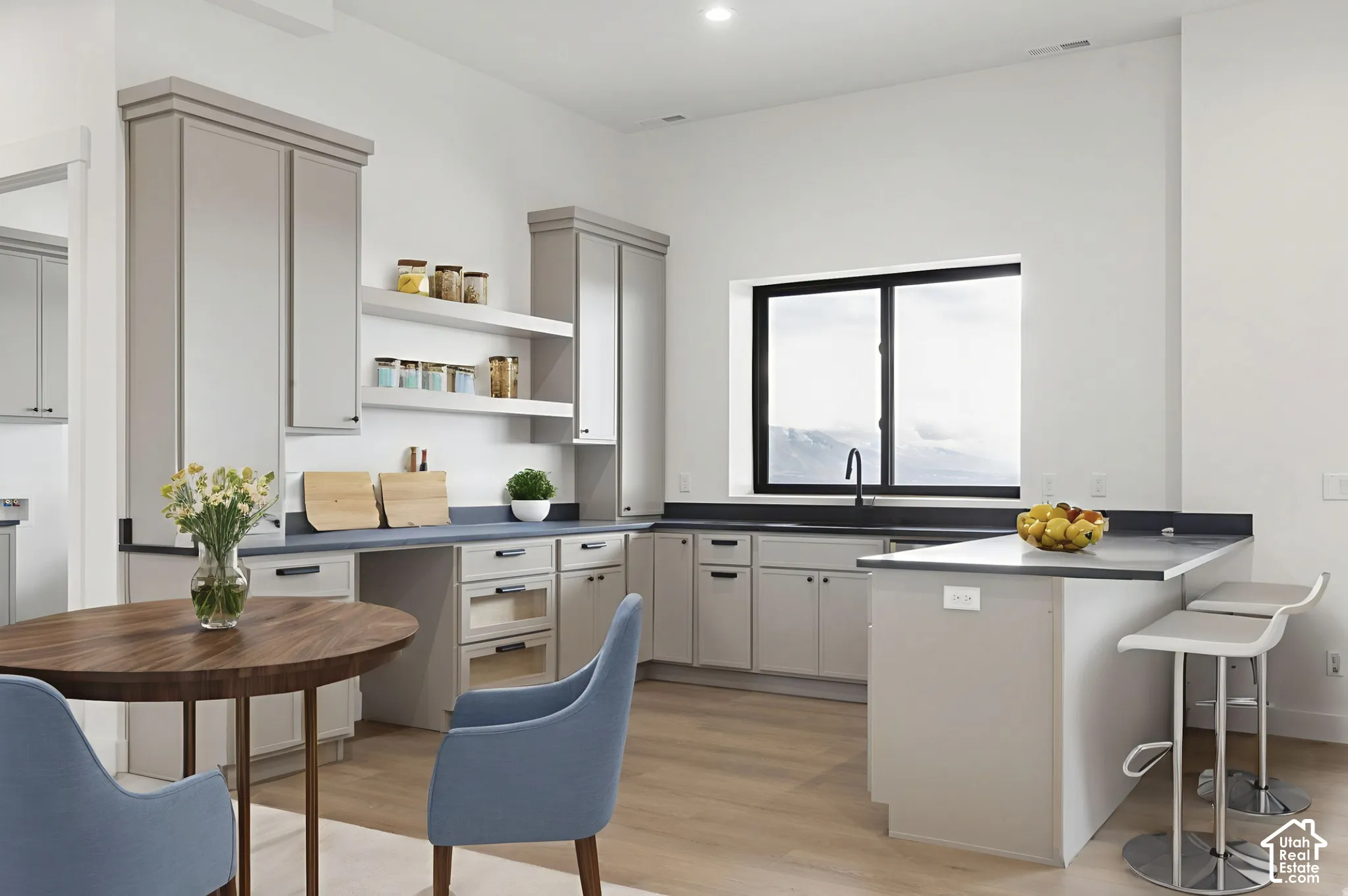 Kitchen featuring shaker-style cabinetry, dark solid-surface countertops, built-in shelving, a kitchen island with seating, and wood-finish flooring