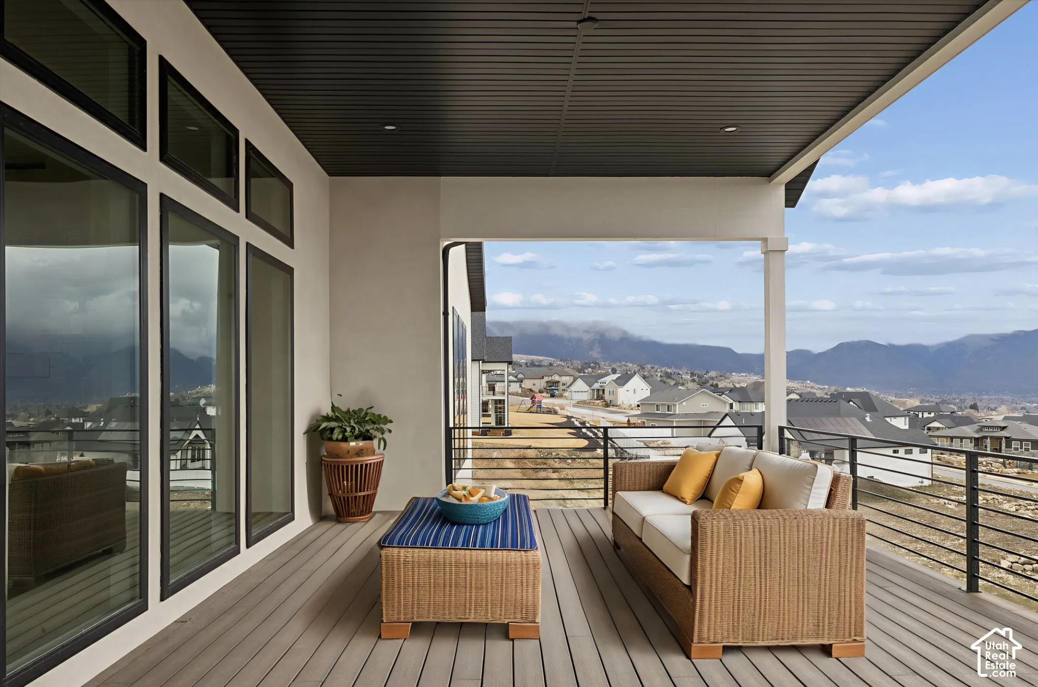 Covered deck featuring composite decking, recessed lighting, black horizontal metal railing, and expansive floor-to-ceiling windows